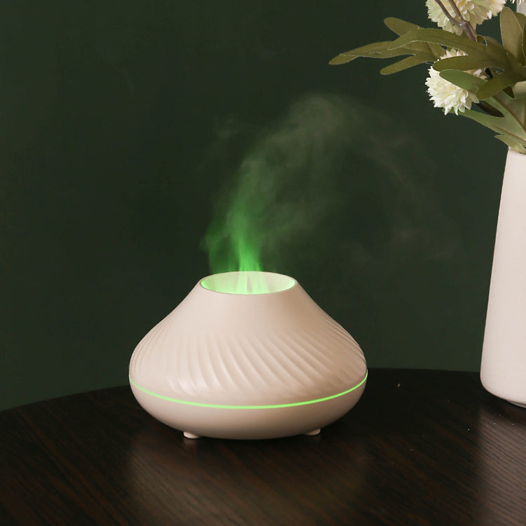 White LavaLux Aromatherapy Diffuser on a table, turned on, with the LED light set to green, and mist coming out like a green flame.