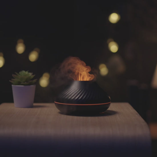 The LavaLux™ Diffuser, in black, with a spectacular golden "flame" effect, in action. In the video, the diffuser is showcased on a bookshelf, on a desk, and on a shelf, with demonstrations of adding water and essential oils. Discover the relaxing atmosphere created by the fine mist and the 7 LED colors, including the golden and blue "flame" effects, for a unique aromatherapy experience.